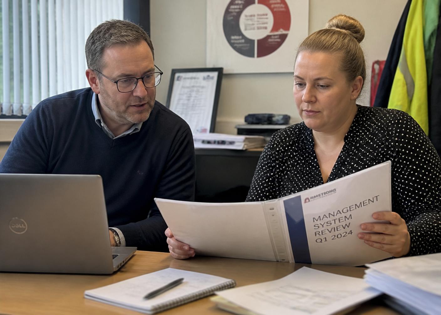 ISO consultant reviewing a management system report with a client ahead of a surveillance audit